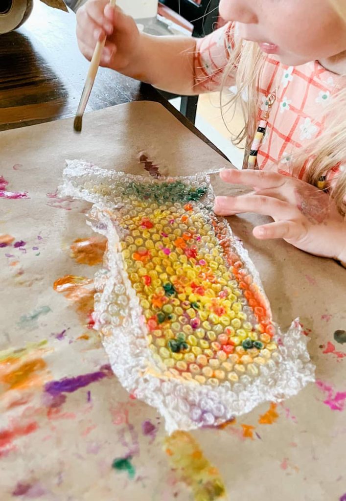 a child painting bubble wrap at the table