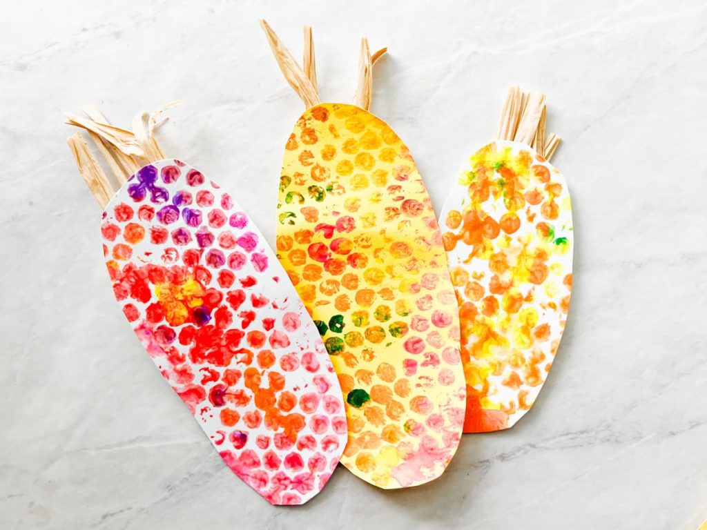 3 finished indian corn crafts out of construction paper and painted bubble wrap sitting on the counter