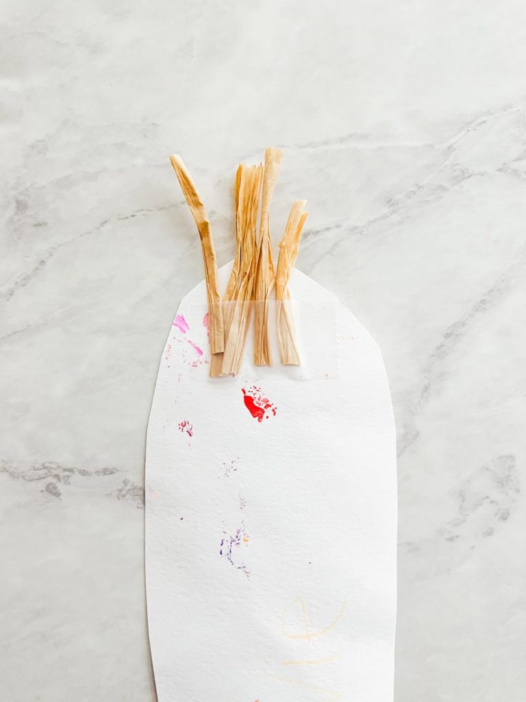 5 small strips of raffia taped to the back of a construction paper corn cob