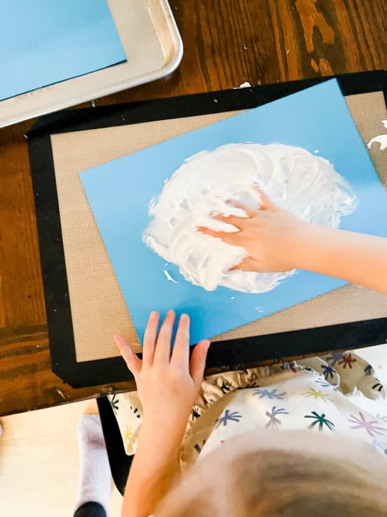 child squishing the puffy paint with her hand on the paper