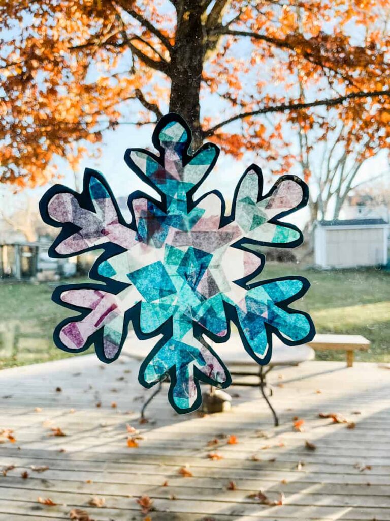 finished snowflake suncatcher on window in front of tree and deck