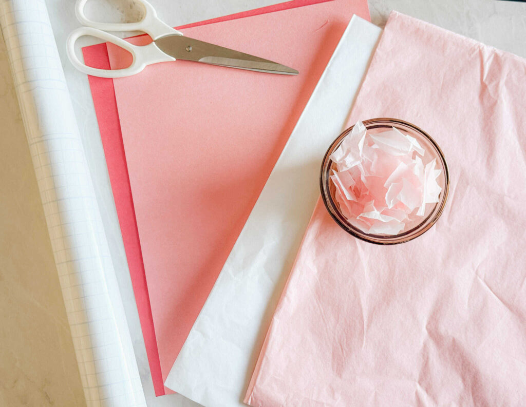 Materials for the heart suncatcher craft including scissors, construction paper , contact paper and tissue paper