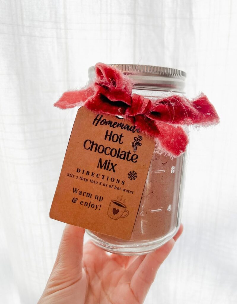 hand holding a jar of homemade hot chocolate mix with gift tag attached