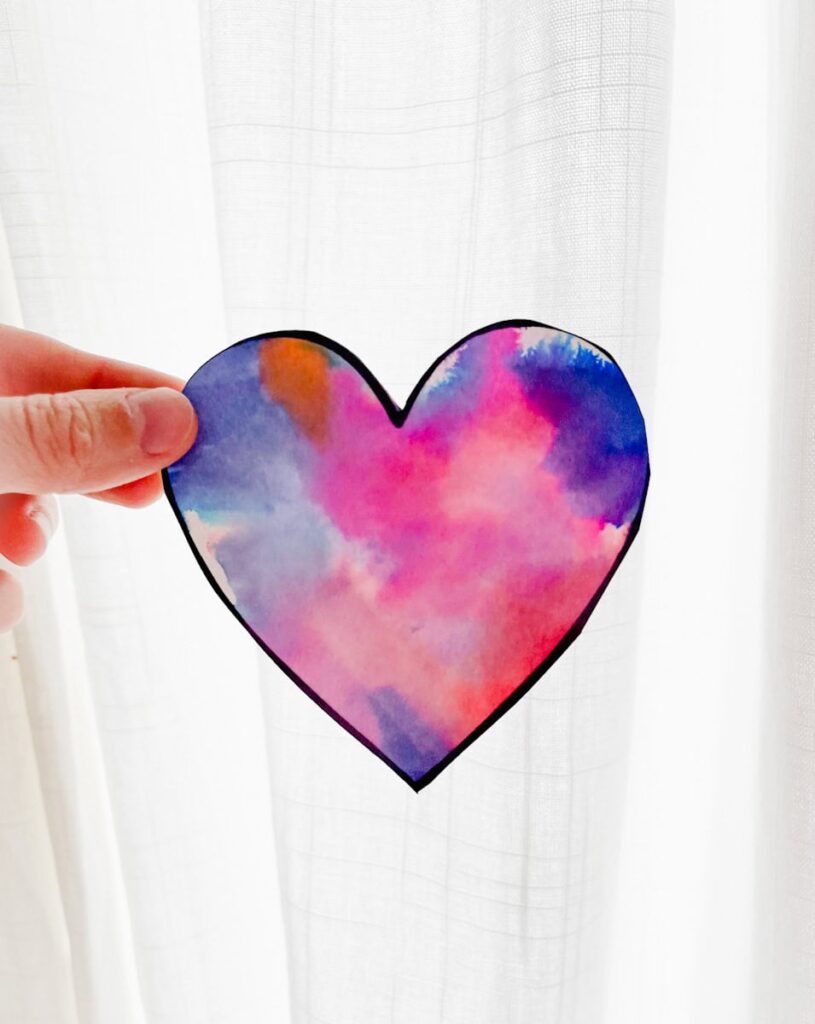 hand holding tissue paper heart in front of curtains