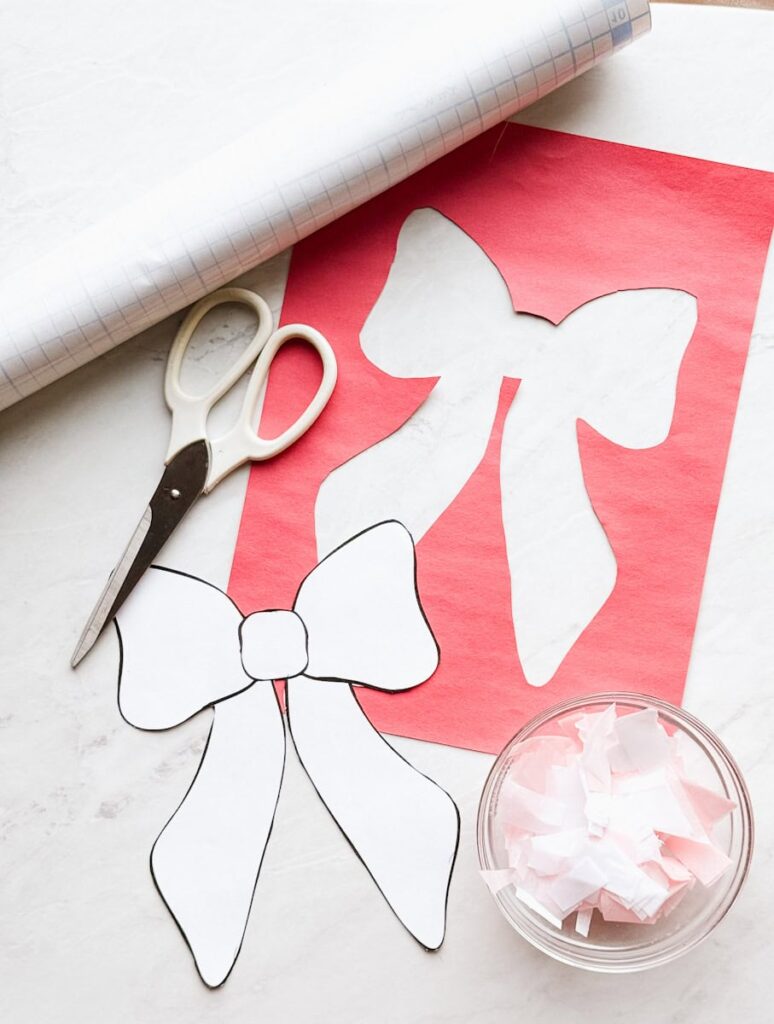 bow shape cut out in construction paper with template, scissors, tissue paper and contact paper out