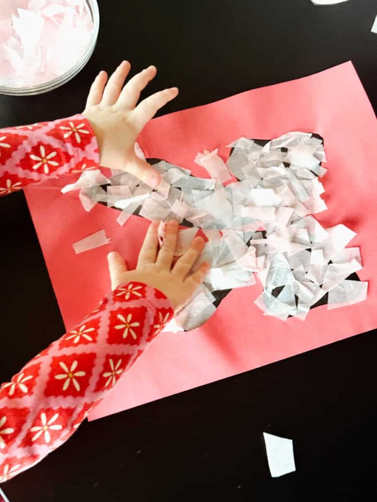 child putting tissue paper on bow suncatcher