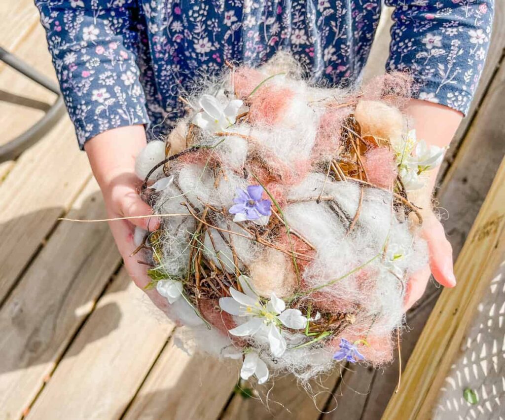 child holding nesting ball for birds while outside