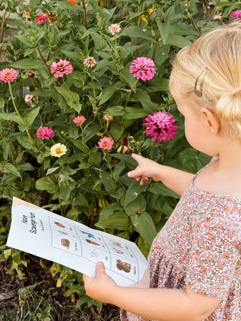 child looking at flowers holding the free printable nature scavenger hunt activity