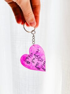 hand holding the shrinky dink keychain in front of white background