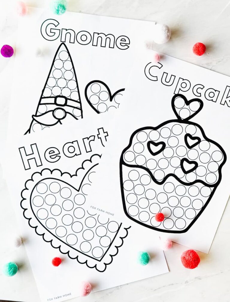 3 of the printable dot marker pages on a table with pom poms around them