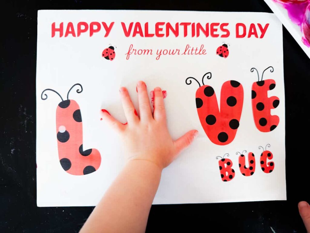 child's hand on the printable paper to make red handprint