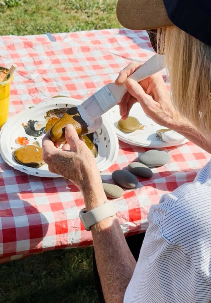 women painting her rock with base color of white
