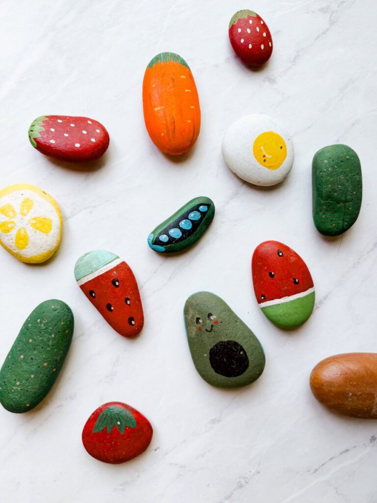 completed painted rocks in a variety of designs of food on table