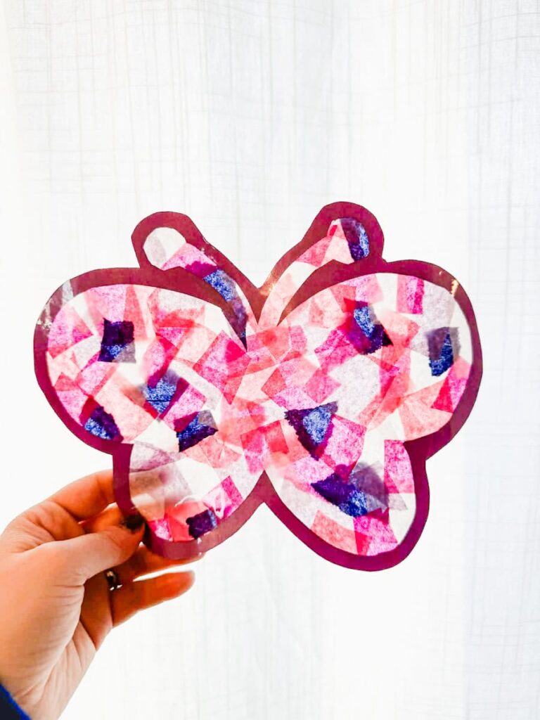 butterfly suncatcher held up in front of white curtains