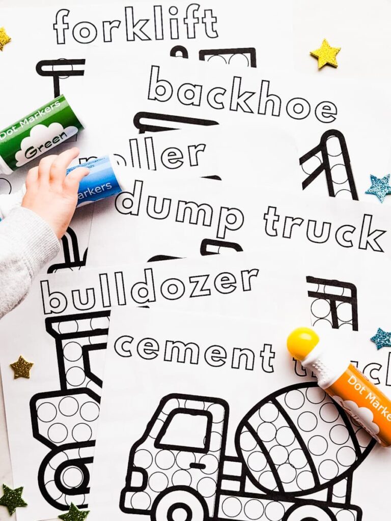 child's hand grabbing dot marker with printable truck pages on table
