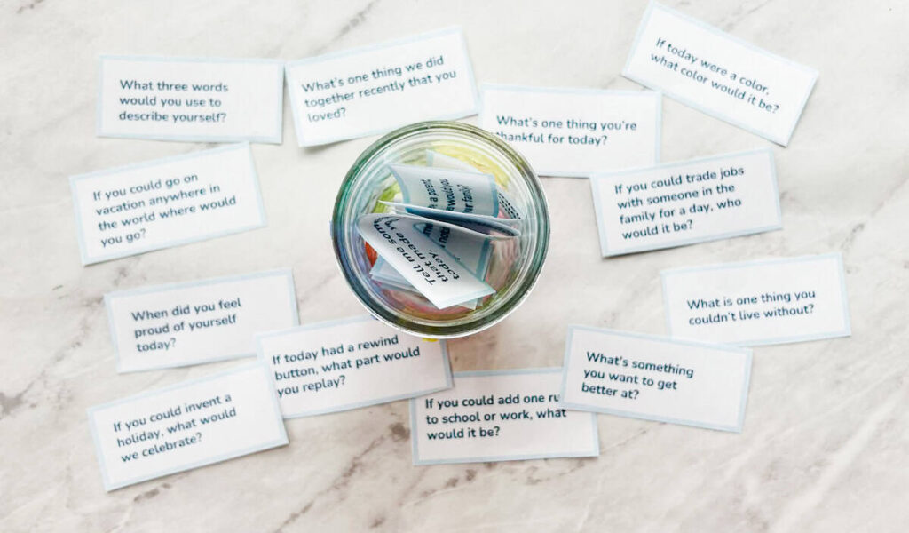 conversation starters in jar and some cards laying on the table next to it