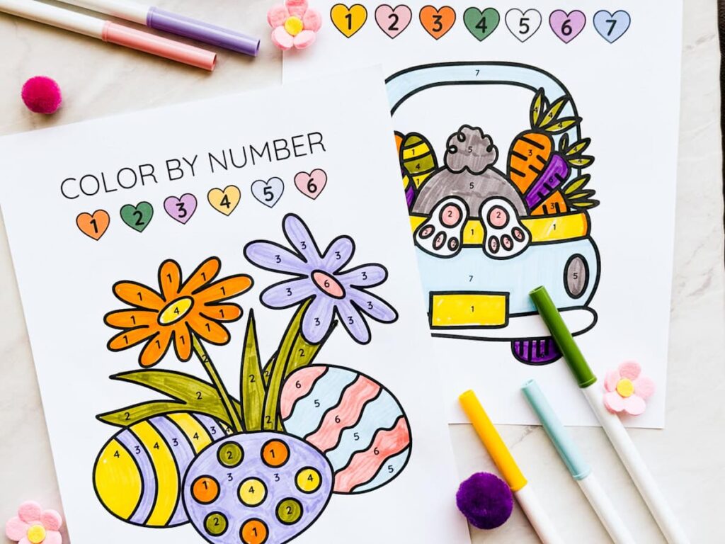 2 finished easter color by number pages on table with markers around it