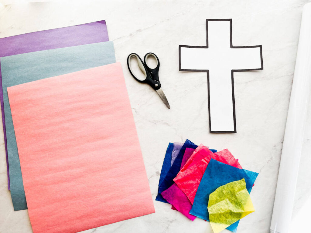 construction paper, scissors, cross template, tissue paper squares and contact paper sitting on the counter