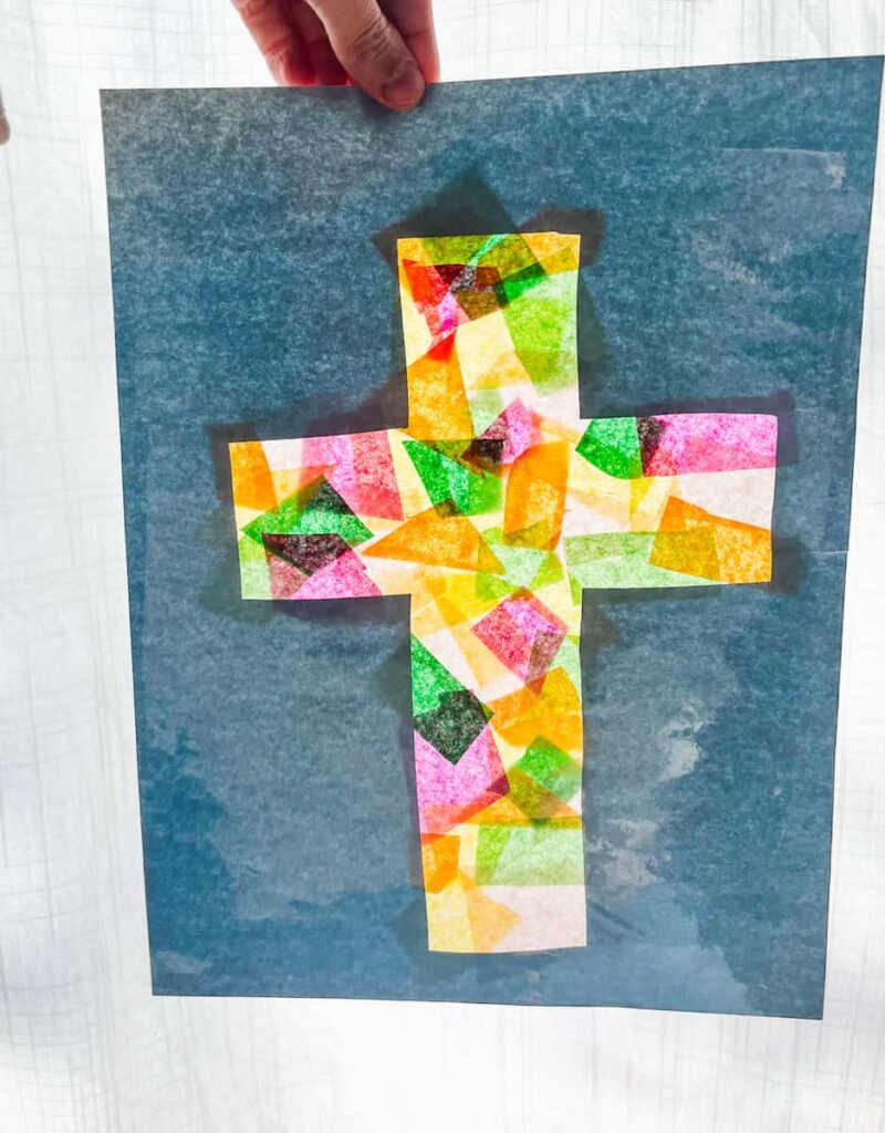 hand holding filled in cross template up to the window