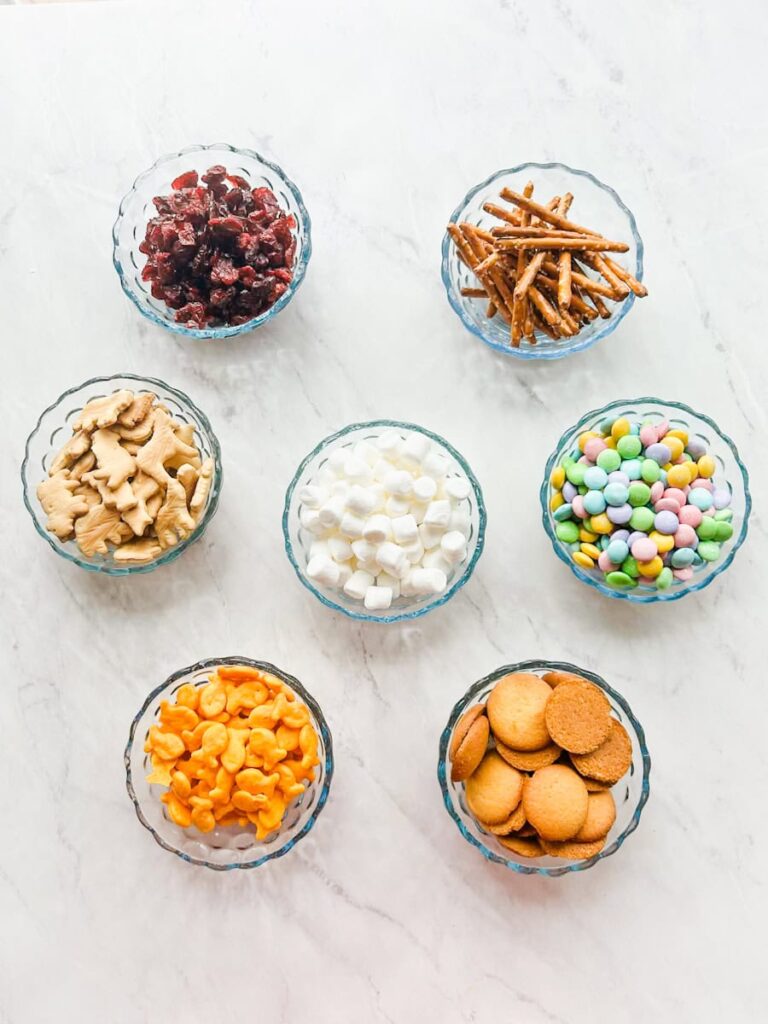7 bowls holding each ingredient for the snack mix