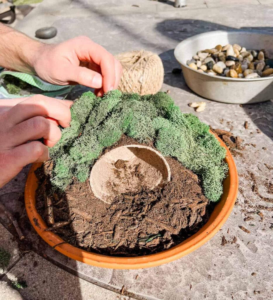 hand putting moss on top of the hill of the diy resurrection garden