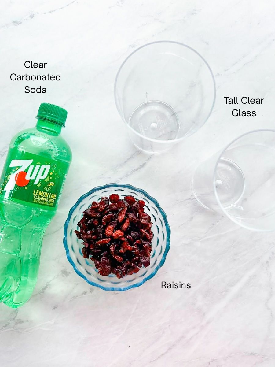 2 clear glasses, 7 up and bowl of craisins sitting on the table to show ingredients for science experiment.
