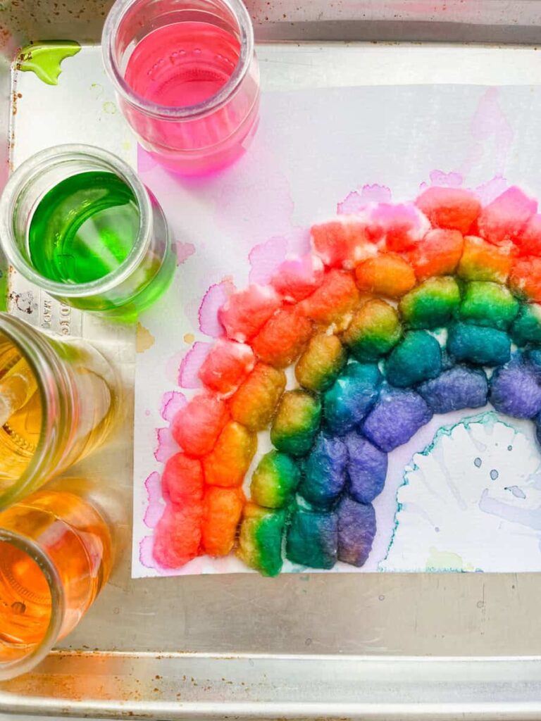 cotton ball rainbow on a tray next to watercolor paints