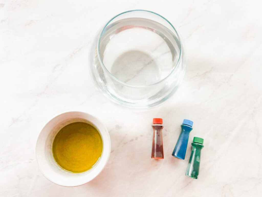 bowl with water, small bowl with oil and food coloring on table