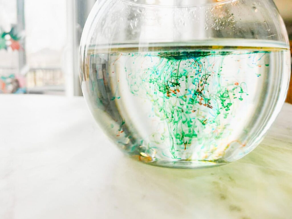 water bowl with the oil and food coloring mixture in it creating fireworks