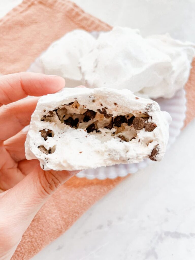 hand holding hollow resurrection cookie in front of plate of cookies