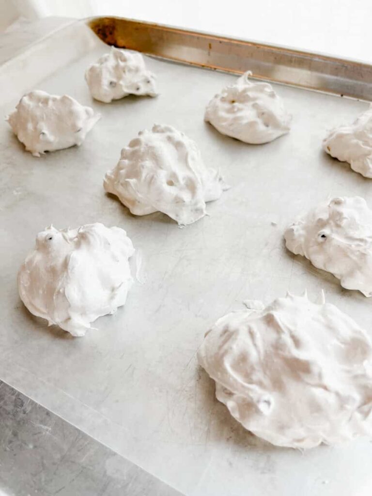mounds of meringue cookies on baking sheet lined with parchment paper