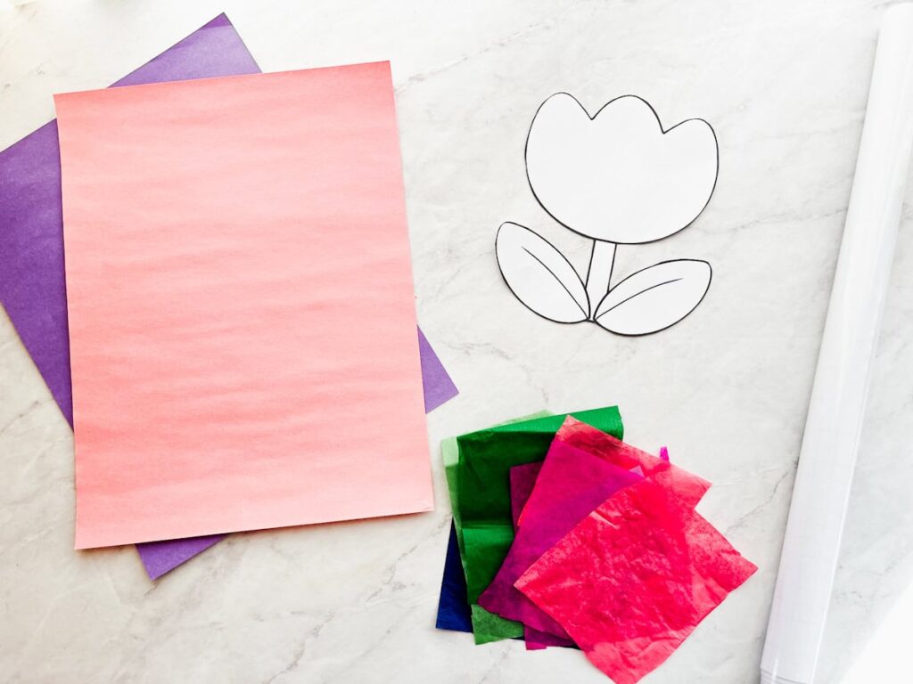 tulip template, construction paper, tissue paper and contact paper on a countertop