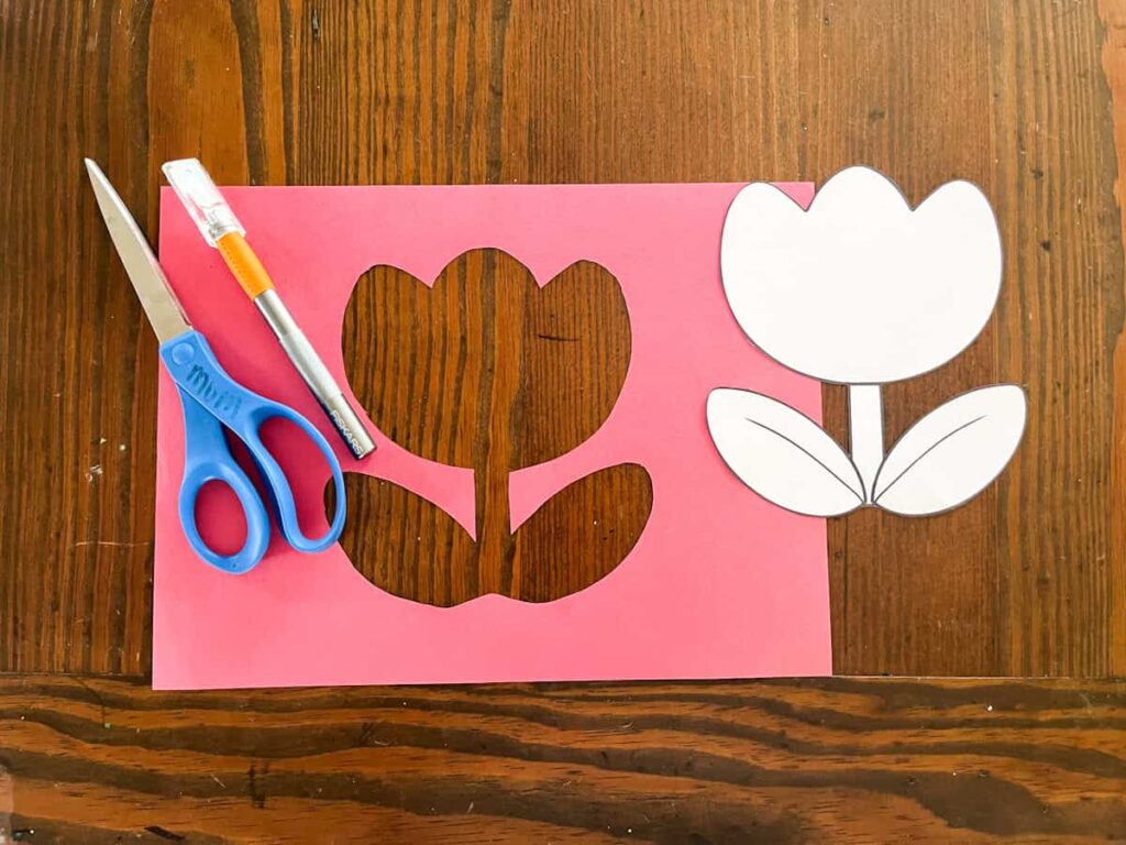 tulip template cut out in construction paper next to scissors and an exacto knift