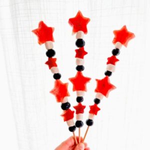 hand holding 3 completed 4th of July fruit kabobs.