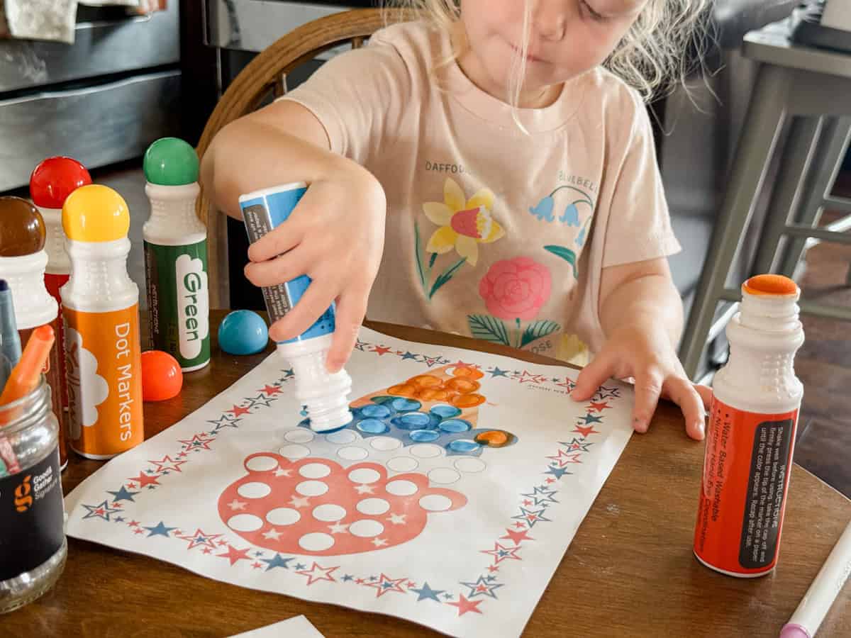 child completing her red white and blue ice cream dot marker page.
