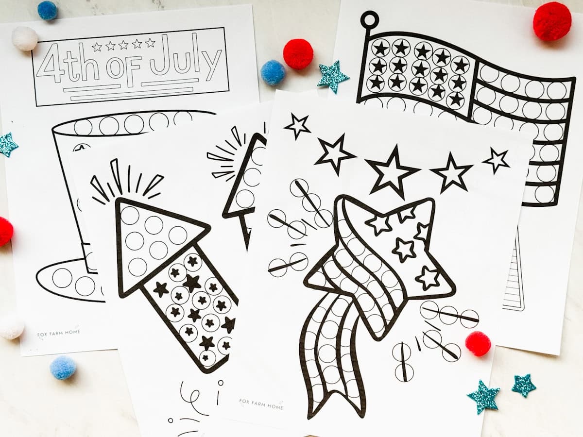 Dot marker pages all on table with red and blue pom poms on table with it.