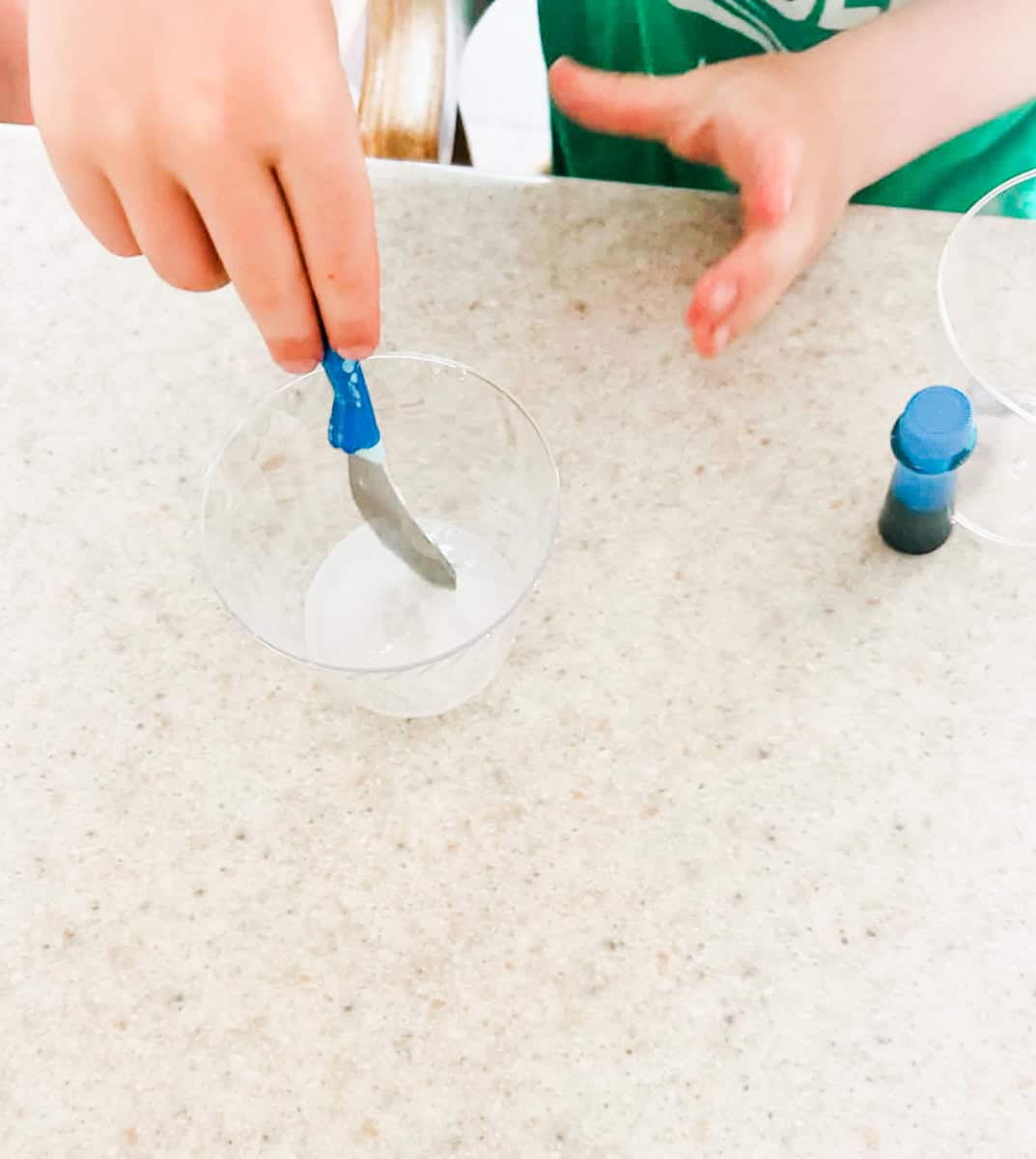 child stirring the borax and water until the borax dissolves.
