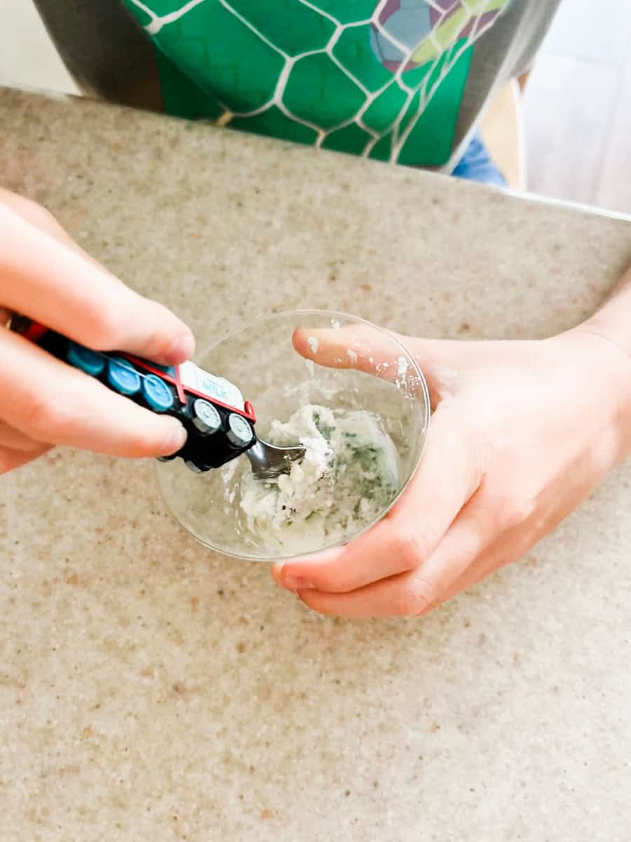 child stirring the cornstarch and glue mixture.
