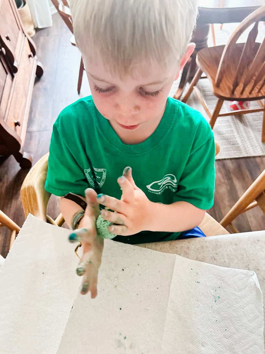 child rolling the bouncy ball between their hands to shape it.