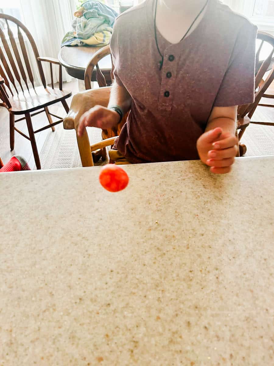 child bouncing ball on table to test it.