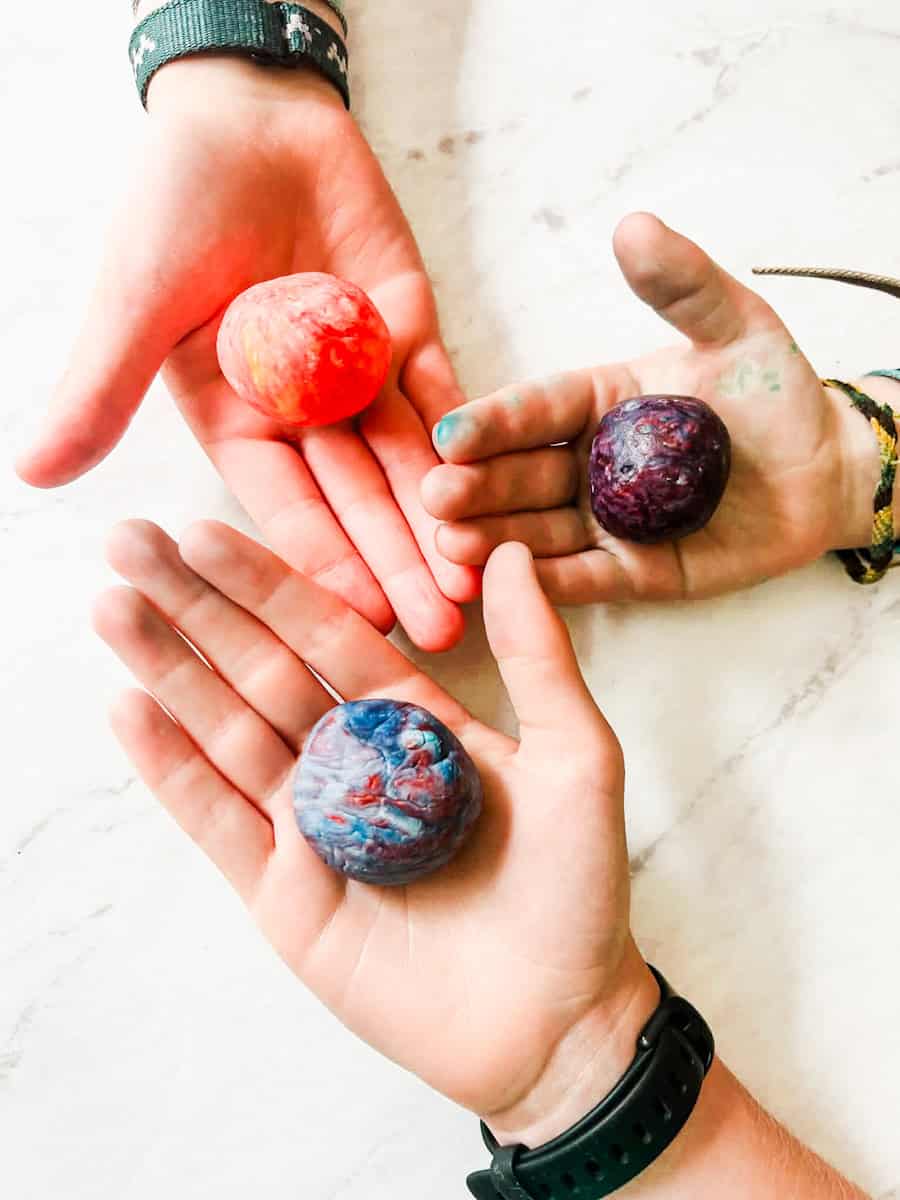 3 hands from kids that are each holding a bouncy ball. 