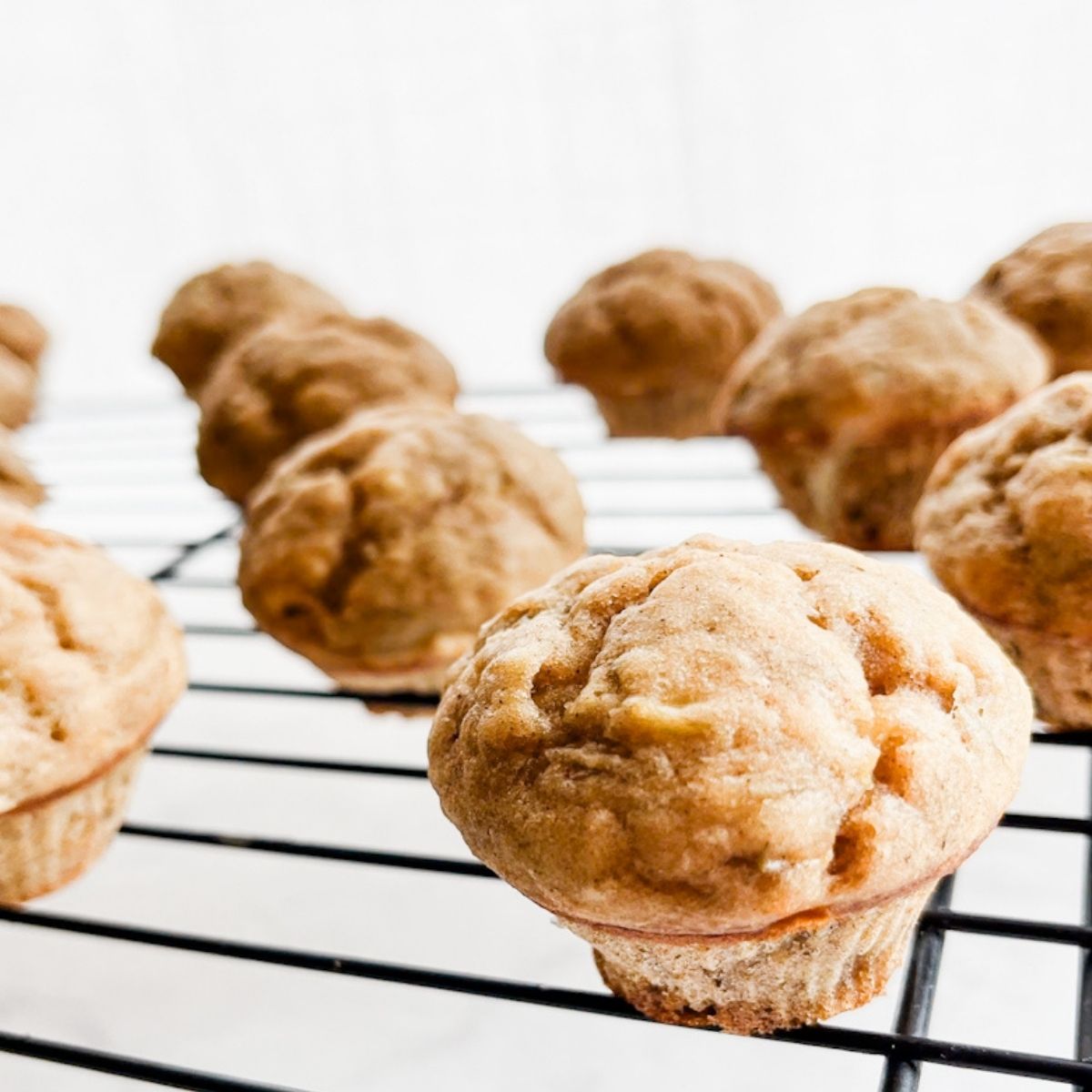 Baked mini banana muffins on a wire rack on the counter.