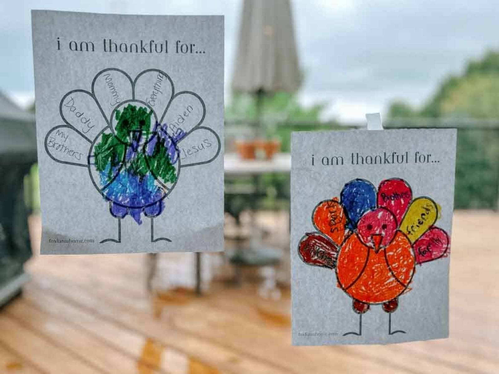 completed I am thankful turkey printables, both hanging on a window.