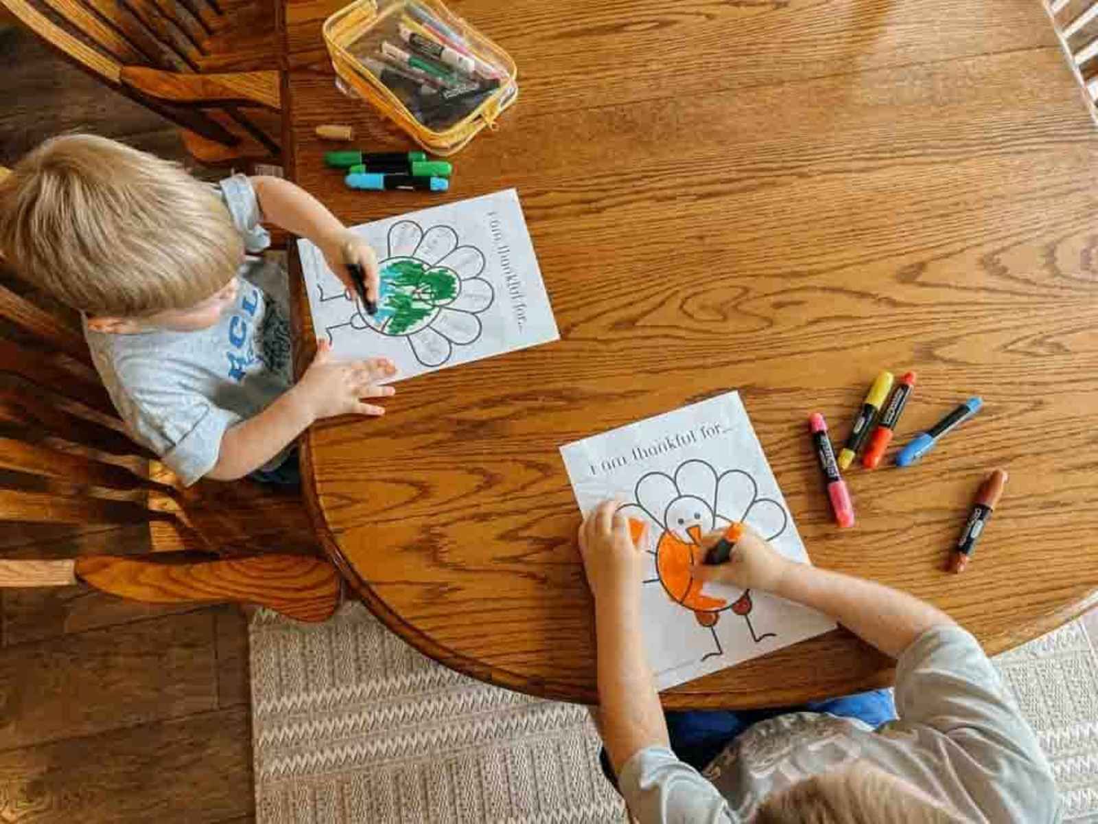 Two children sitting at table coloring their turkey printable.