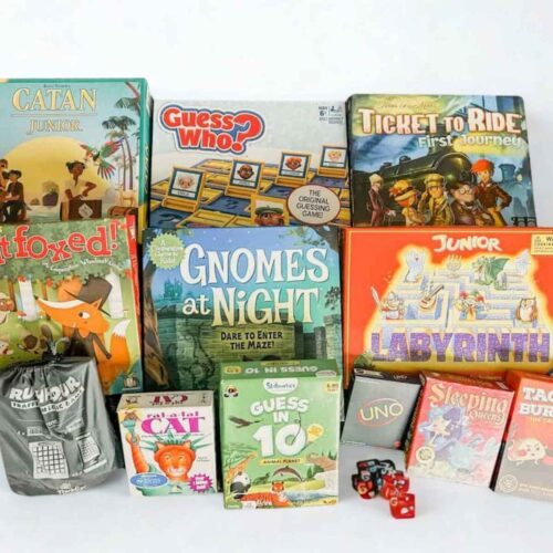 lots of board games piled on table, includes the games in boxes and dice on the table.