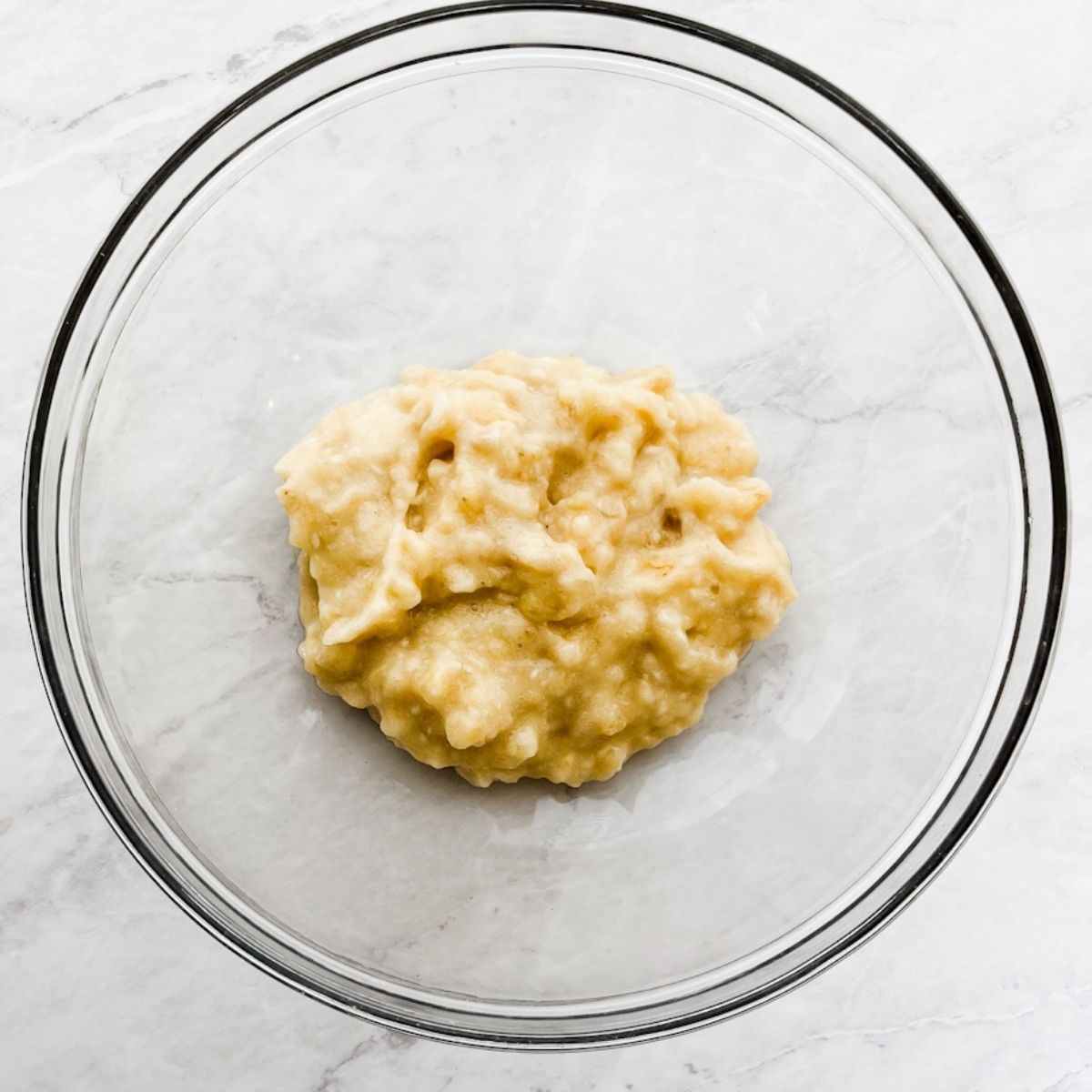 Mashed bananas in a bowl on the counter.