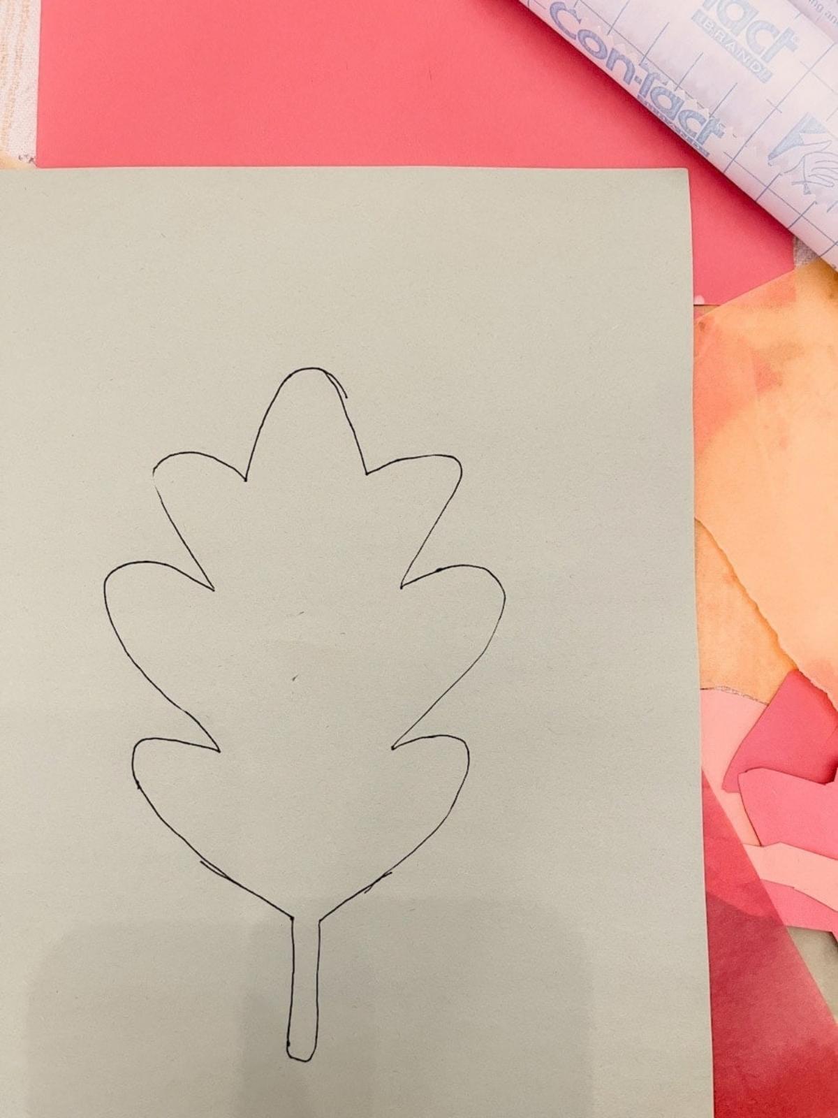 leaf outline on construction paper sitting next to tissue paper and contact paper.
