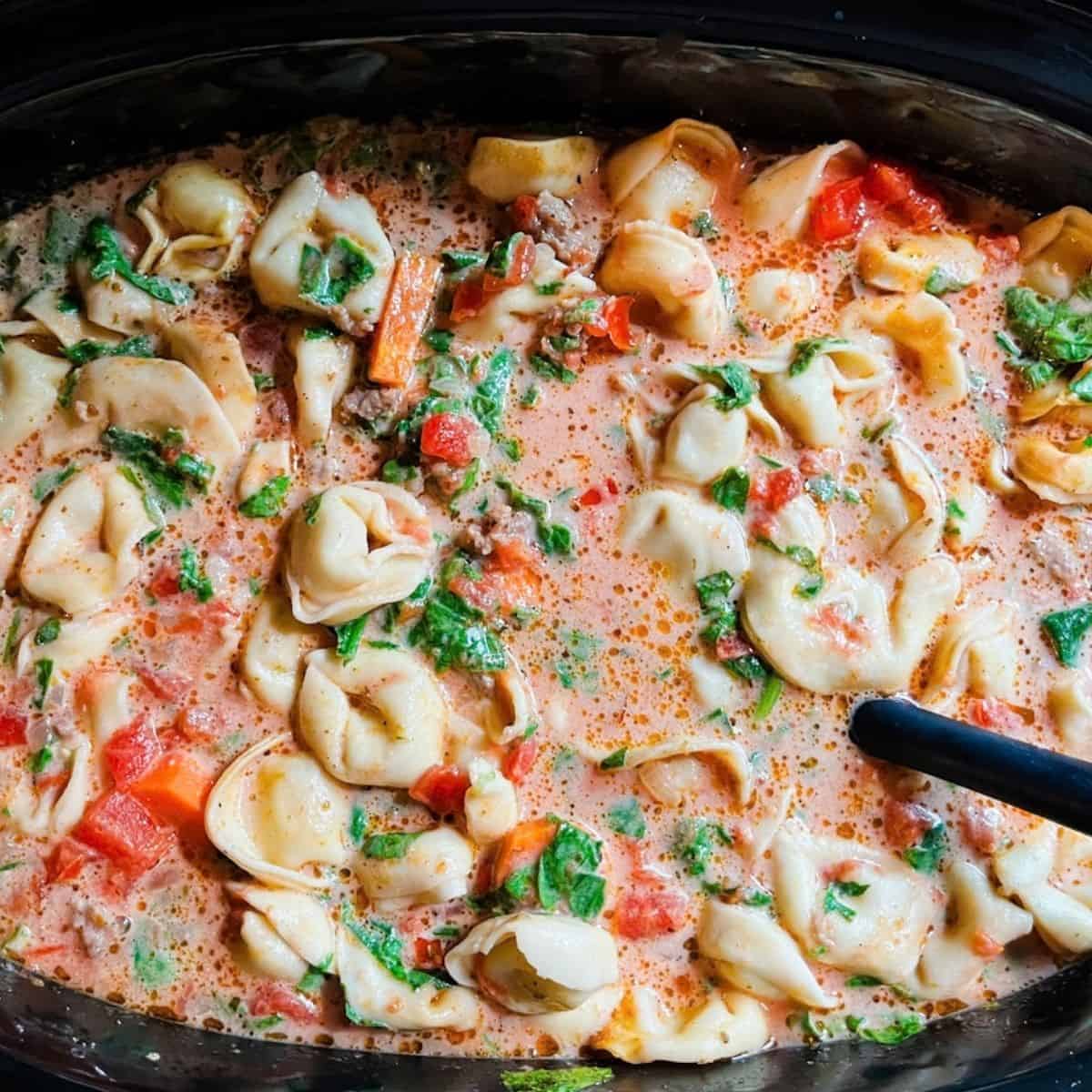 Tortellini soup with sausage mixed together in the crockpot.