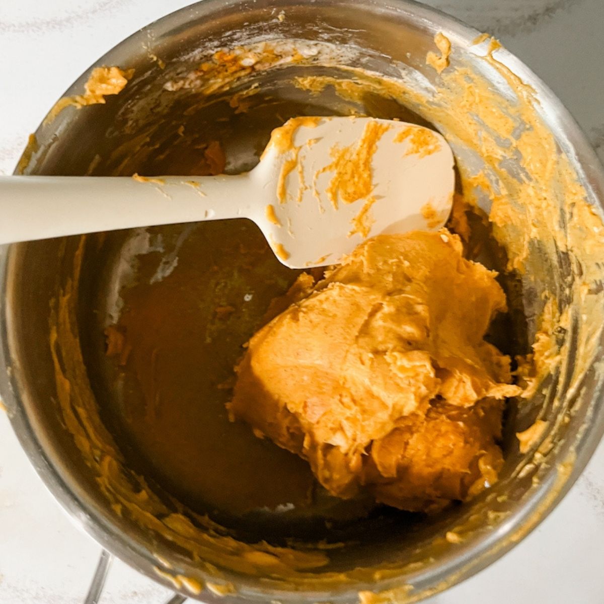Spatula in a pan on the stove as the dough begins to form a ball.