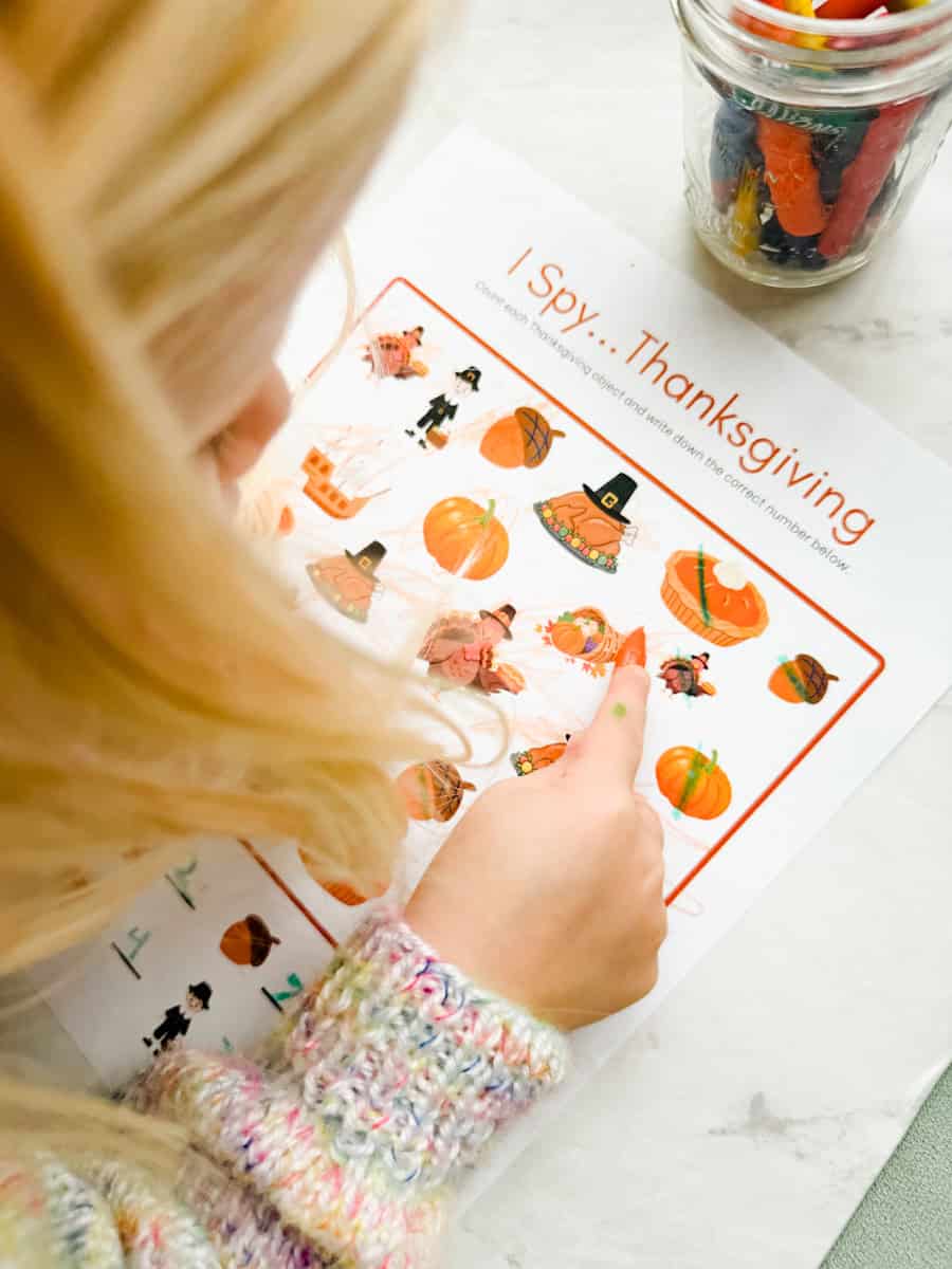 child counting items on the Thanksgiving I spy printable worksheet.